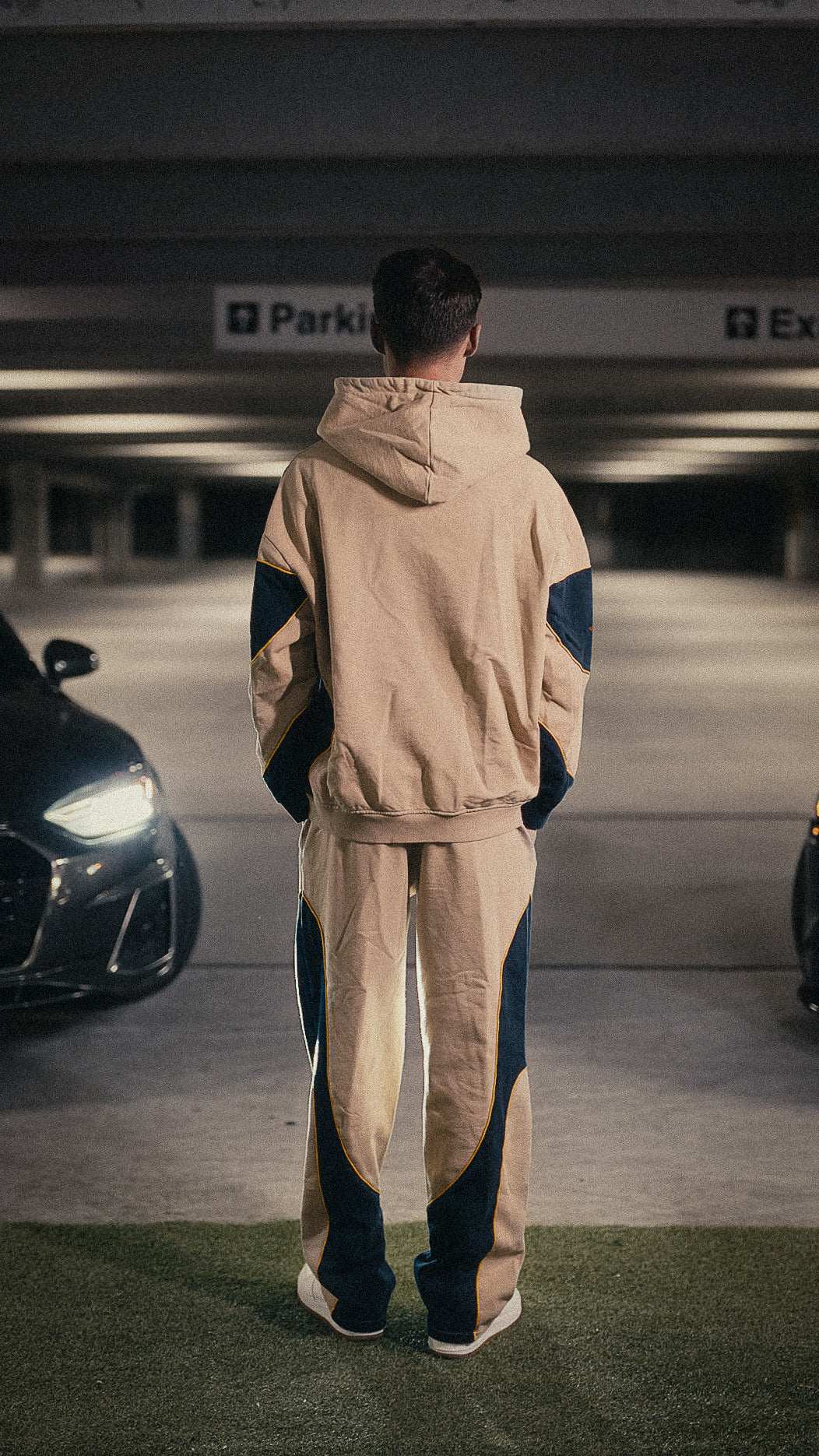 Motorsport set, zip-up hoodie and joggers in neutral tones, modeled in an urban setting.