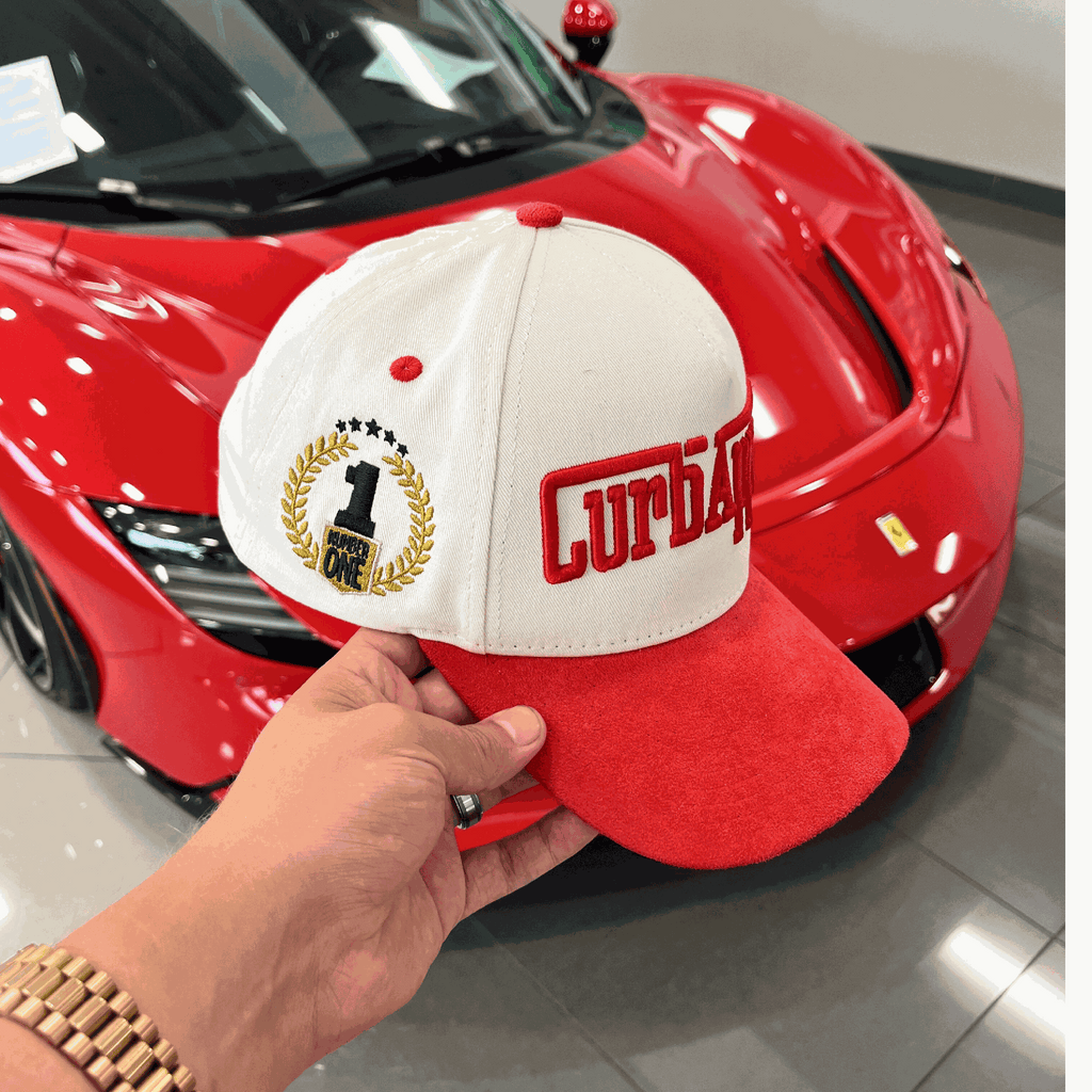 The Winner's Circle Hat with red suede bill and 3D stitching, inspired by racing culture.