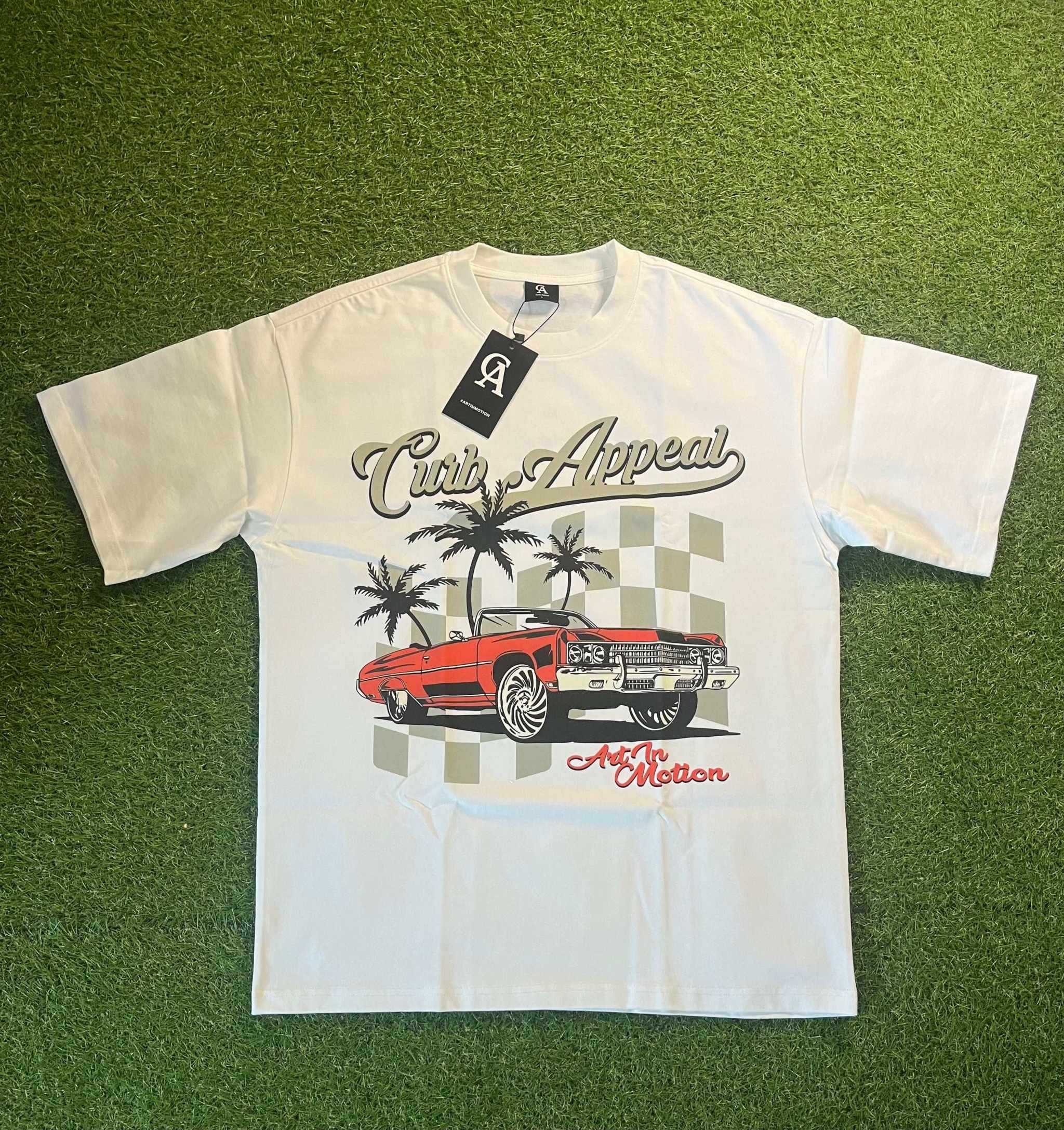 Donk Tee featuring a vibrant graphic design with a red car, palm trees, and an urban theme on a white T-shirt.