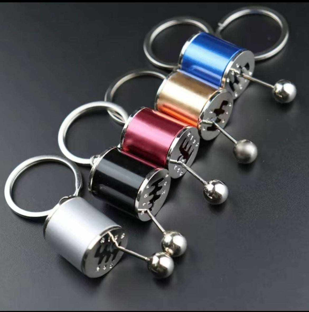 Shifter keychain in various metallic colors mimicking a sports car gear shifter, designed for car enthusiasts.