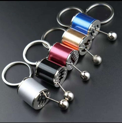 Shifter keychain in various metallic colors mimicking a sports car gear shifter, designed for car enthusiasts.