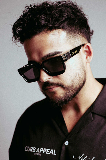 High Roller Shades worn by a person, featuring sleek black frames with gold detailing and dark lenses.