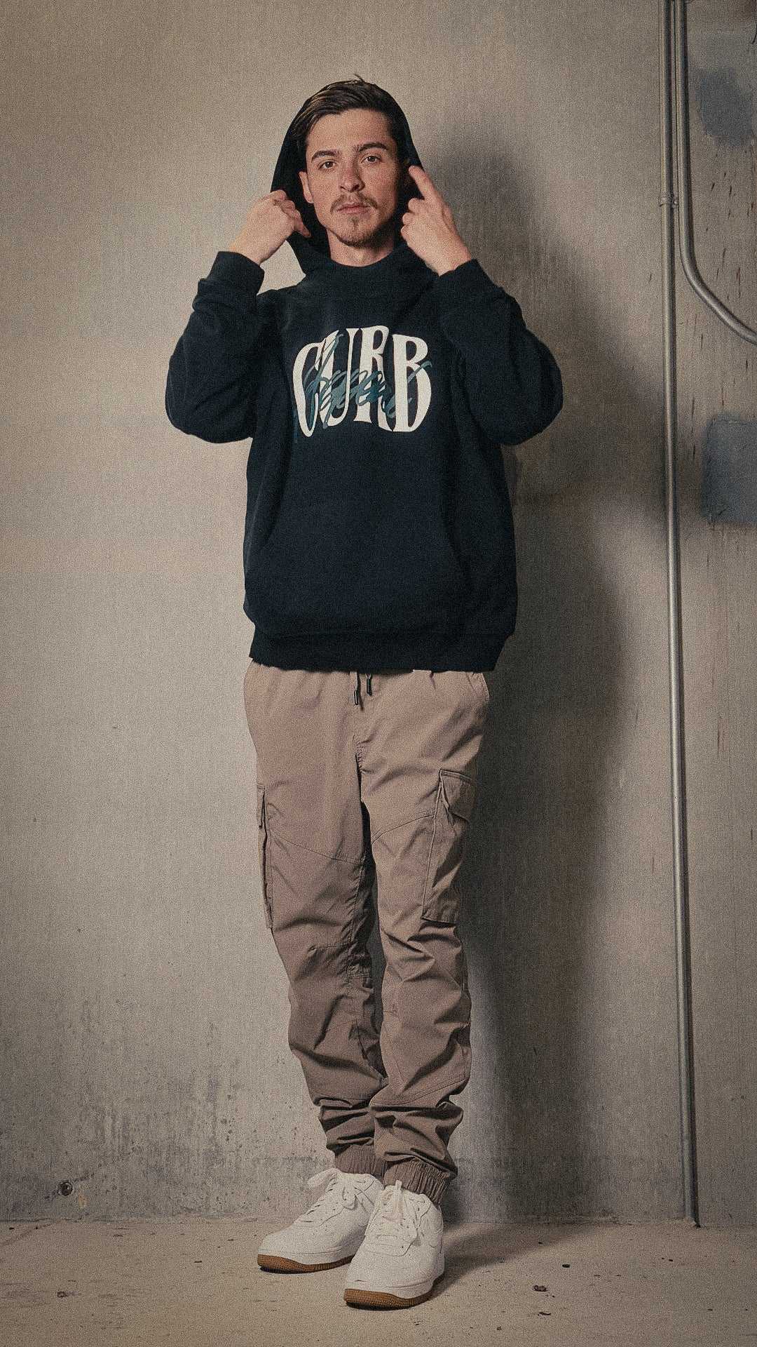 Soft high neck hoodie in black, featuring "Curb" print, modeled for warmth and style.