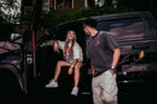 Two people wearing Widow Maker Tees, standing by a black SUV.
