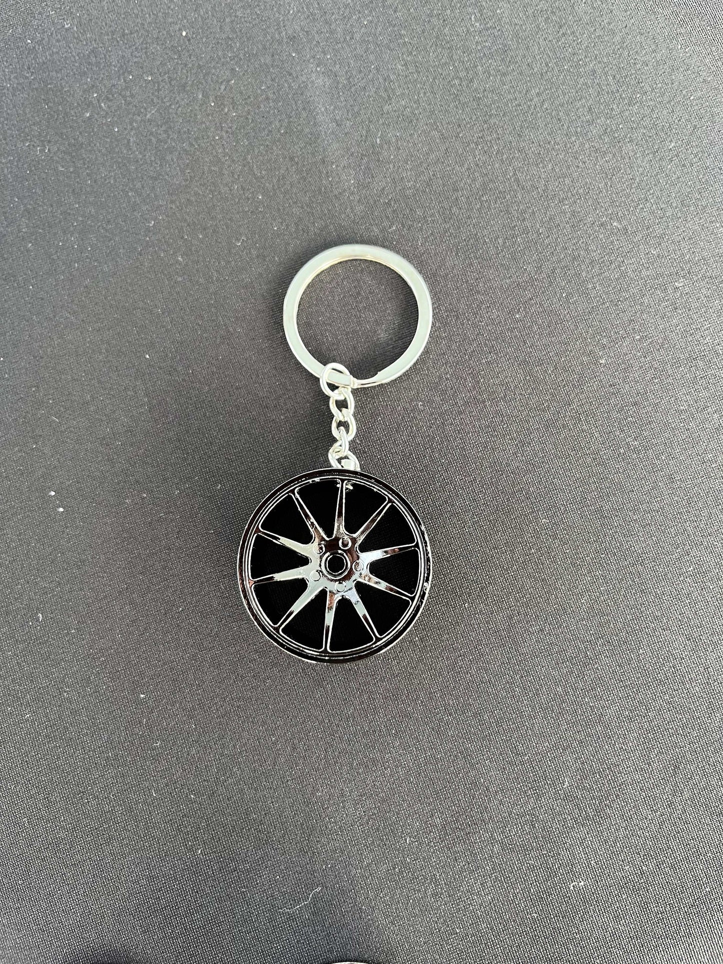 Wheel keychain in black finish with durable design and racing wheel inspiration.