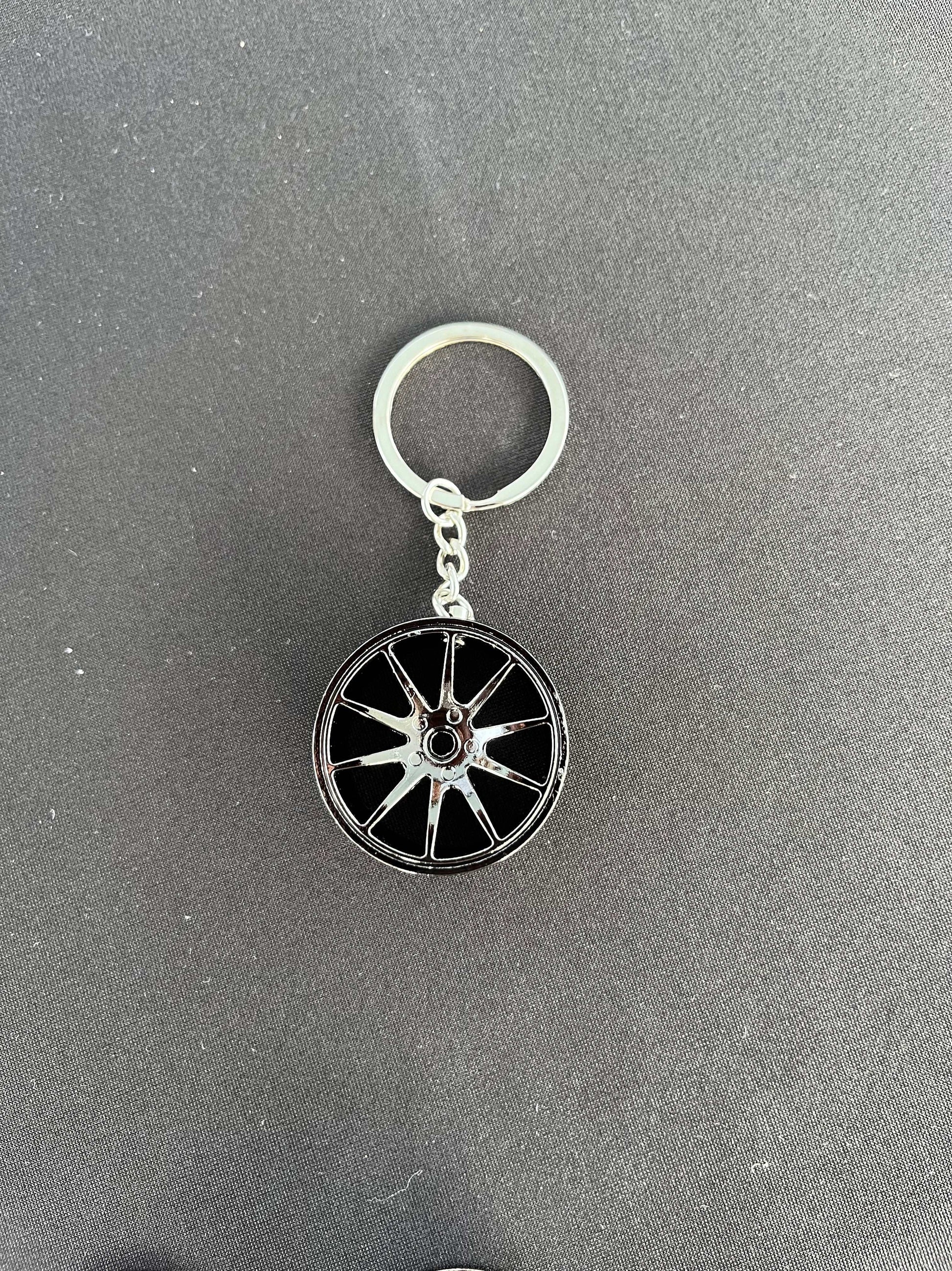 Wheel keychain in black finish with durable design and racing wheel inspiration.