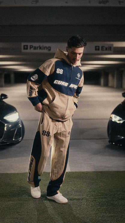 Motorsport set featuring zip-up hoodie and joggers in a relaxed fit, modeled in a parking garage.