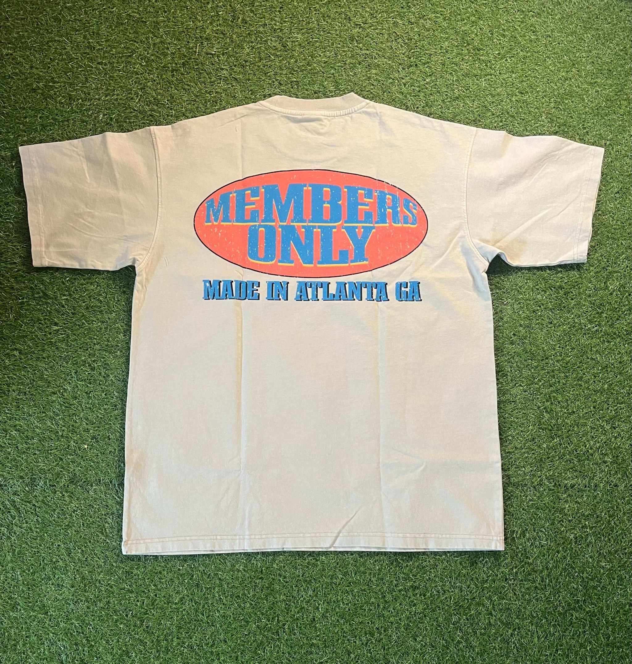 Members Only tee with bold graphics, designed in Atlanta, on a grassy background.