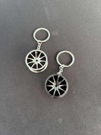 Wheel keychain with car rim design on a black background.