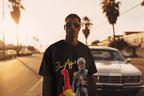 Man wearing oversized black RBF1 Tee with racing driver graphic and number 1 print on street at sunset