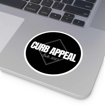 Black and white round logo sticker on a laptop.