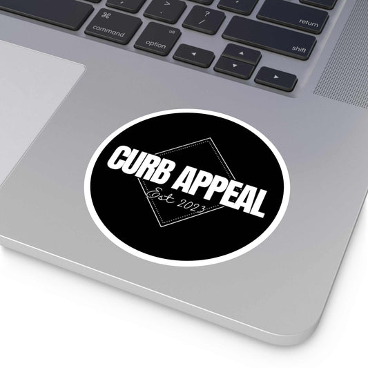 Black and white round logo sticker on a laptop.